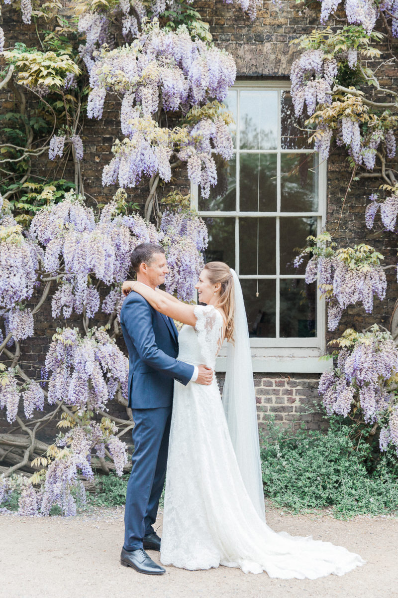 Bride and groom against a backdrop of whisteria at Fulham Palace wedding venue in London