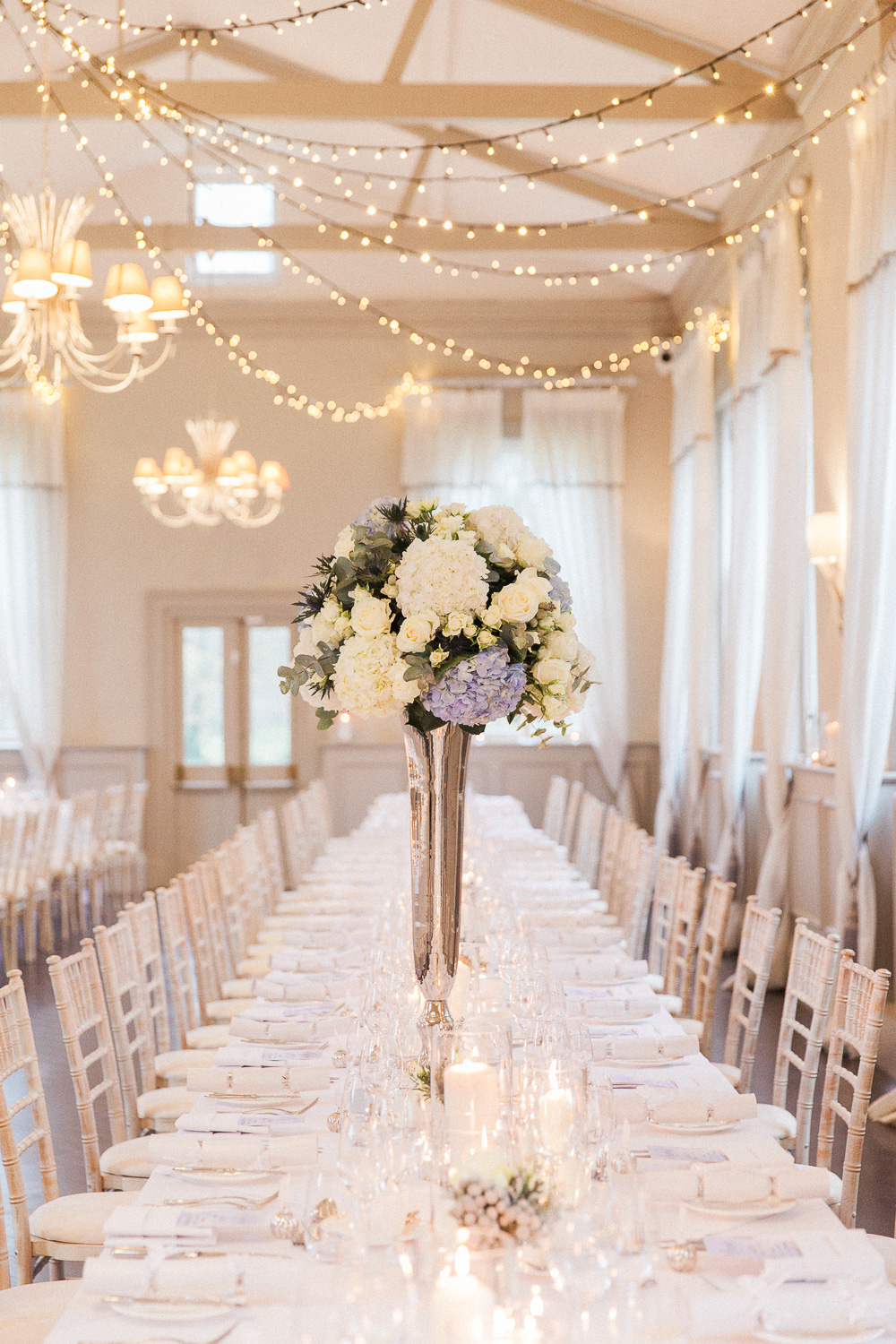 Reception table with blue and white centerpiece and fairy lights at Morden Hall wedding venue in London