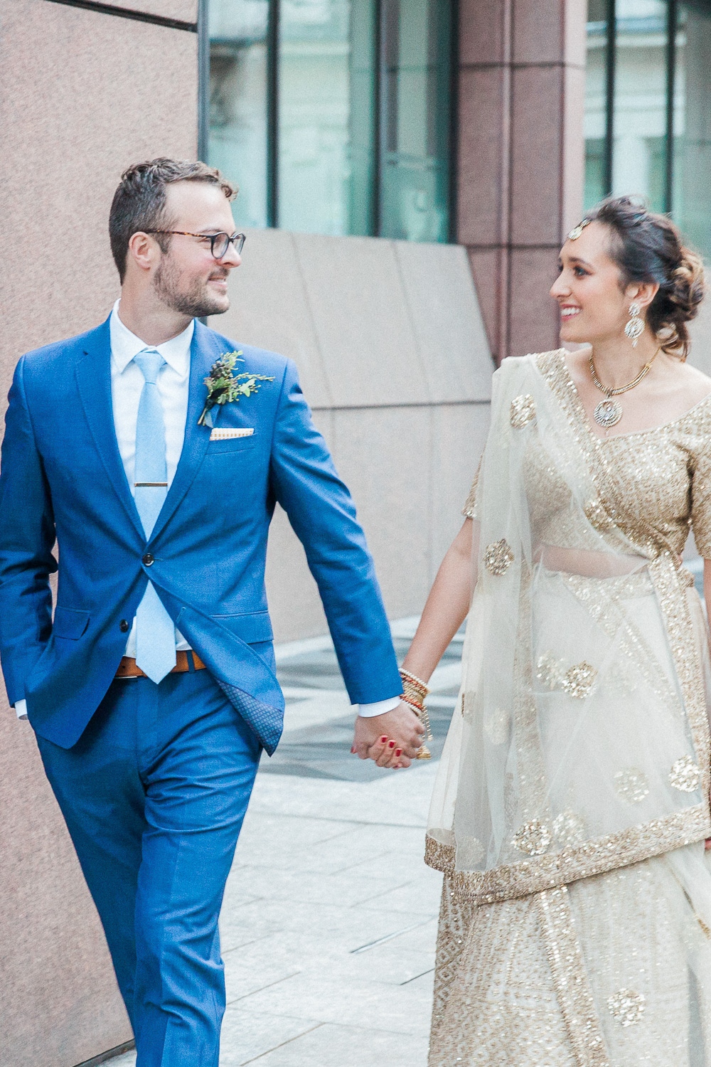 Bride and groom hold hands during their multicultural London wedding