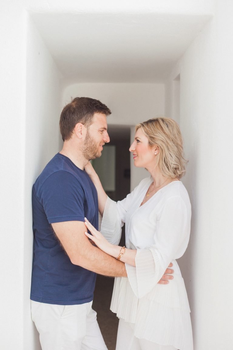 Couple smile at each other in a whitewashed corridor during their shoot at Artemoulas Studios Mykonos