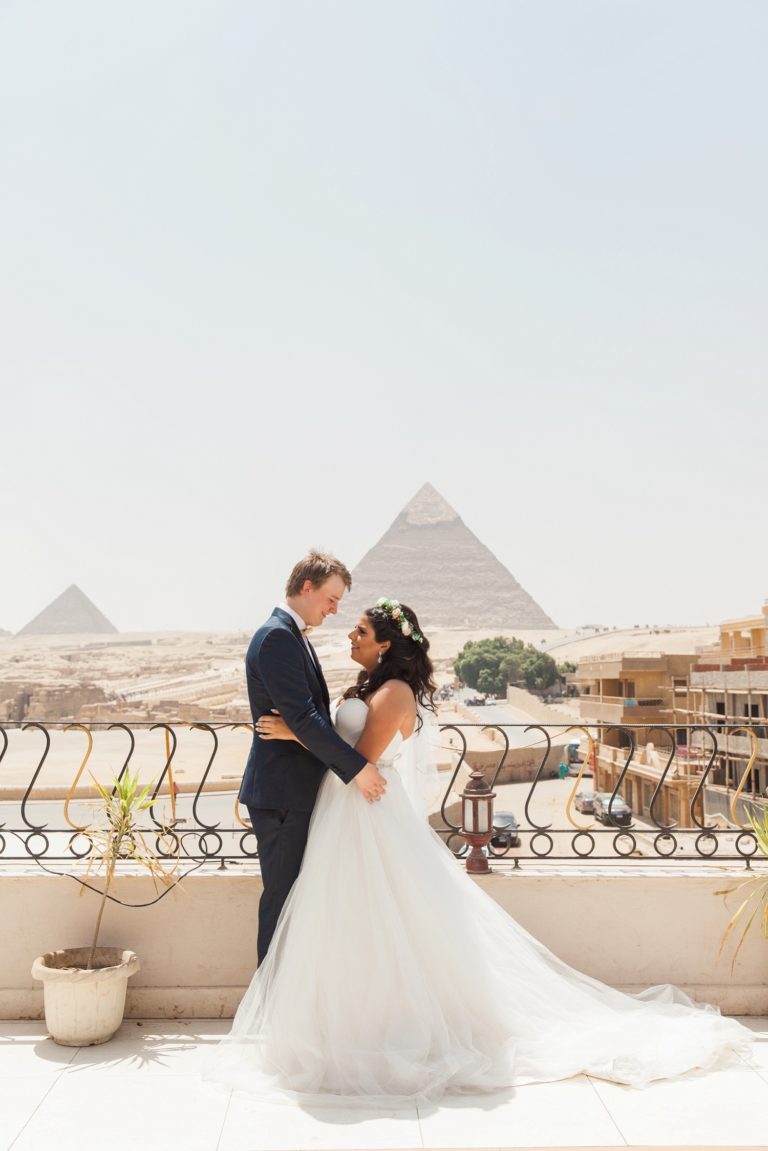 Bride and groom stand together in front of the Great Pyramids of Giza during their Egypt wedding in Cairo