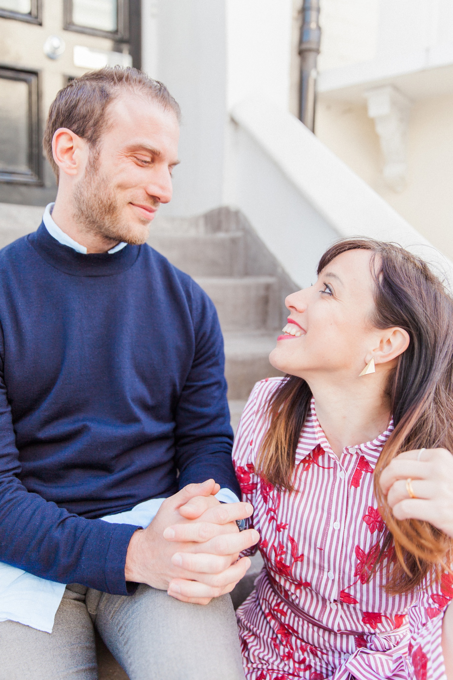 Couple sit smiling at each other on the steps of a house in Hampstead Village