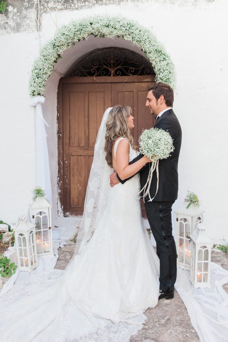 Bride and groom smile at each other outside the church door in Santa Maura Castle in Lefkada