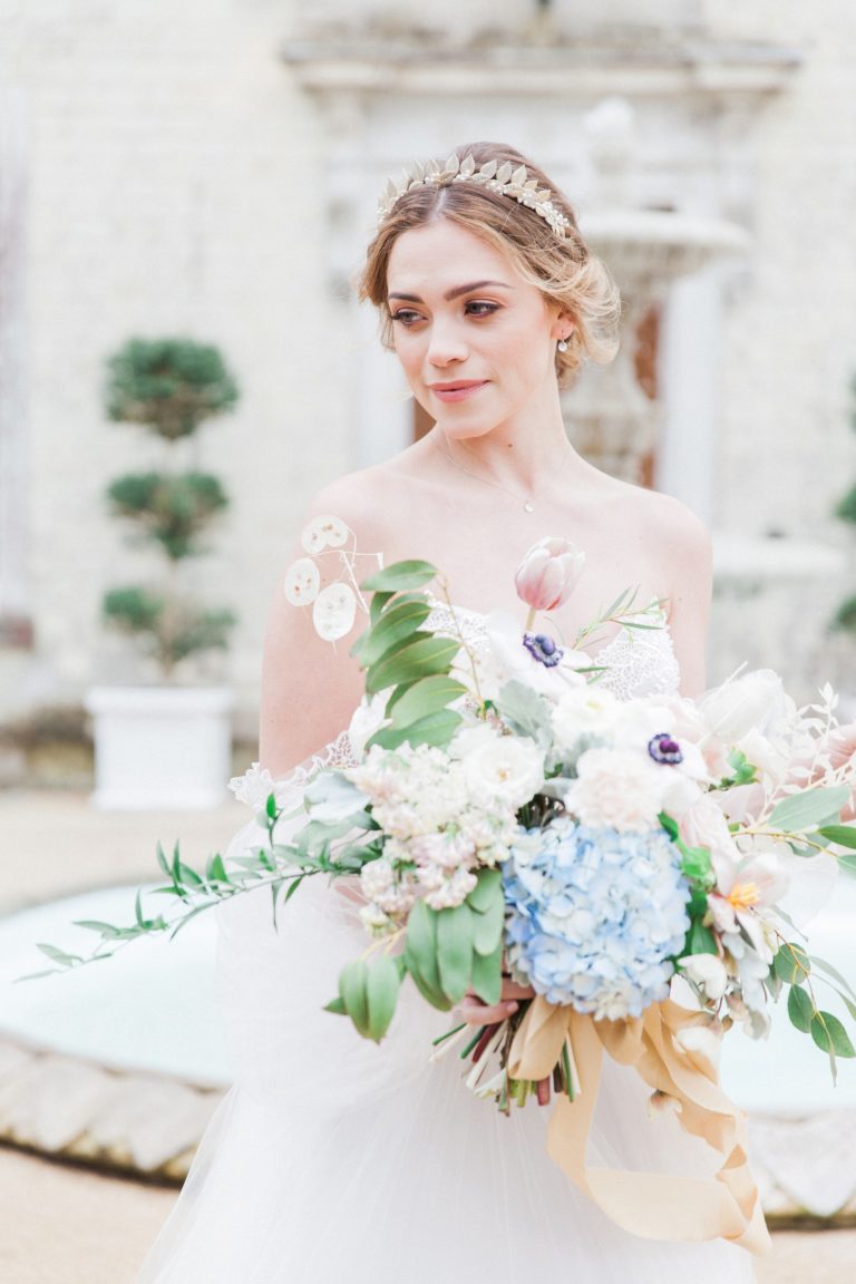Bride holding a pastel bouquet in front of Froyle Park wedding venue