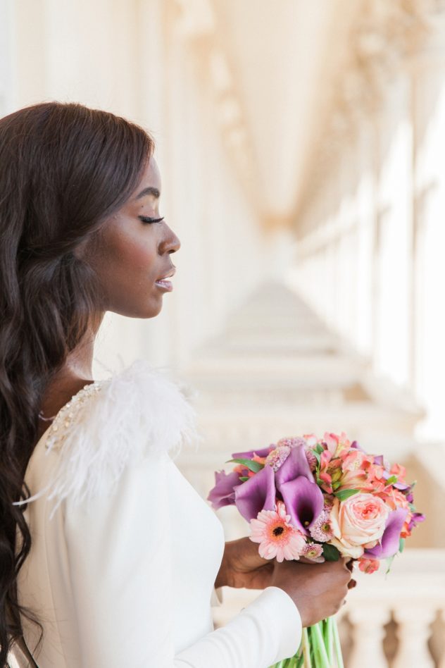 Beautiful black bride on a balcony in London holding a colourful bouquet