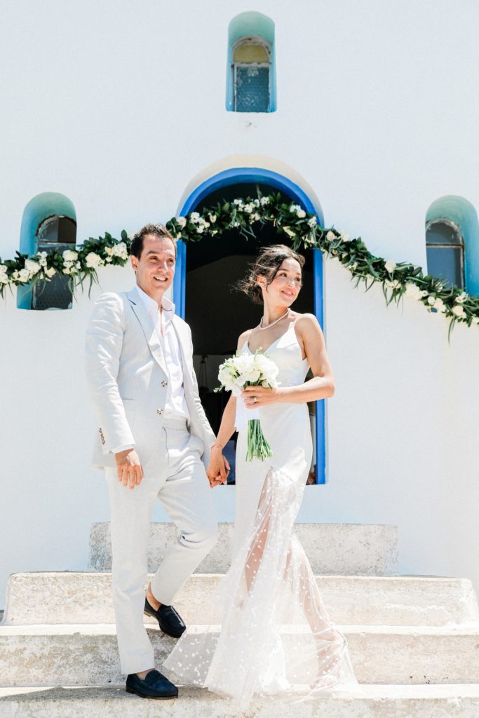 Bride and groom stand together on the stairs of Agios Andreas church on Ithaca