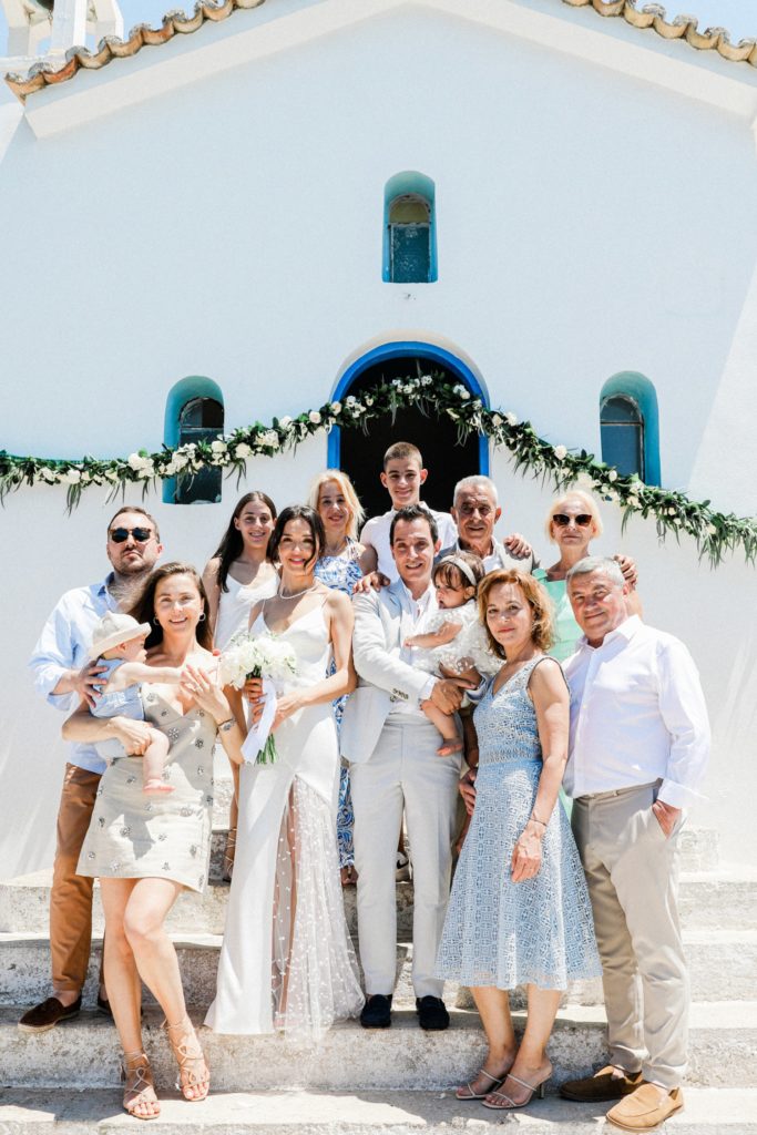 Bride and groom stand with their family on the stairs of Agios Andreas church on Ithaca
