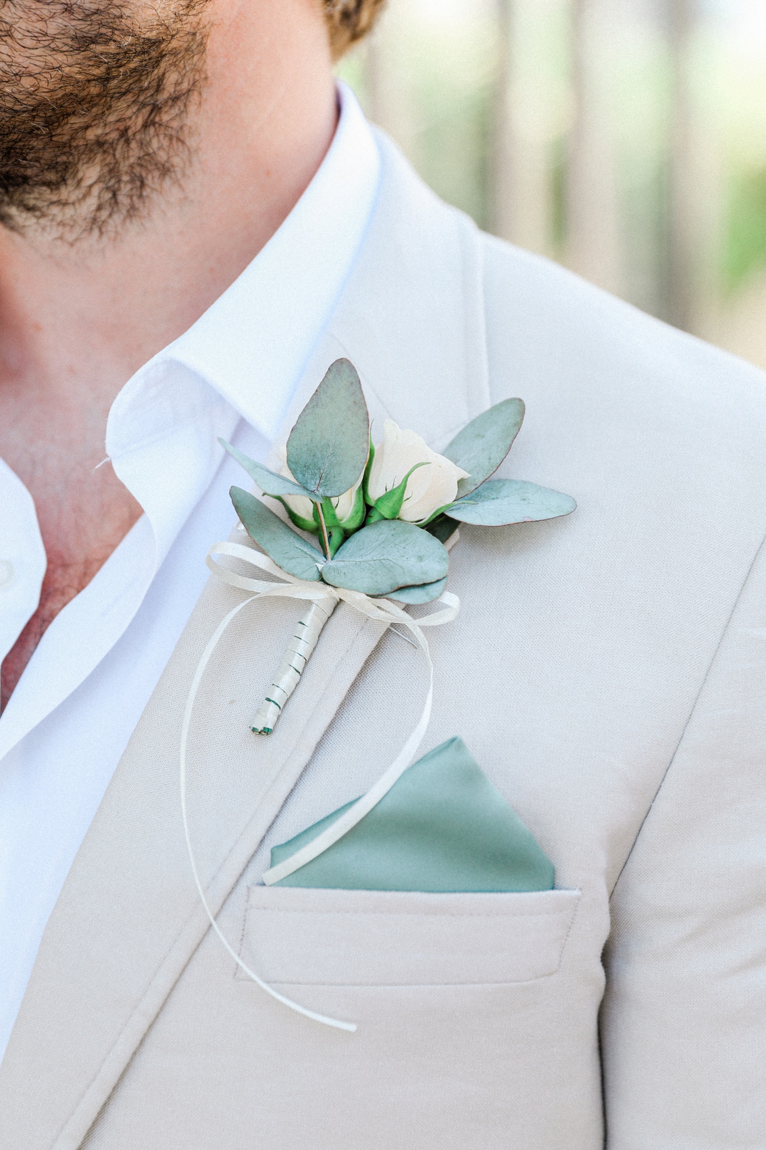 Grooms eucalyptus and rose buttonhole on a stone suit with a sage green pocket square