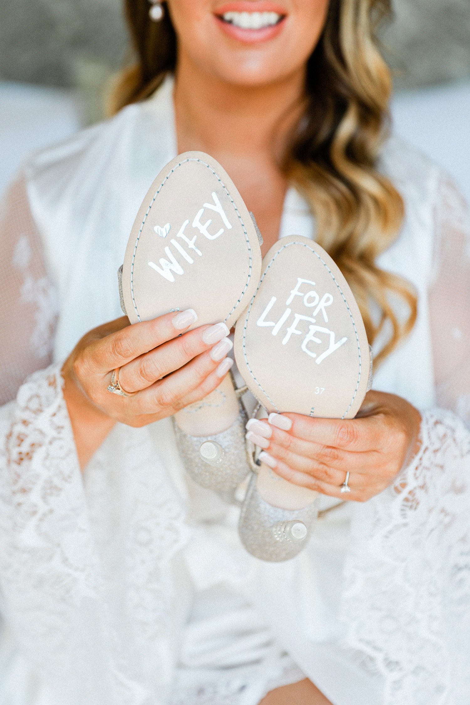 Bride shows off her Sophia Webster bridal heels with Wifey for Lifey detail on the soles