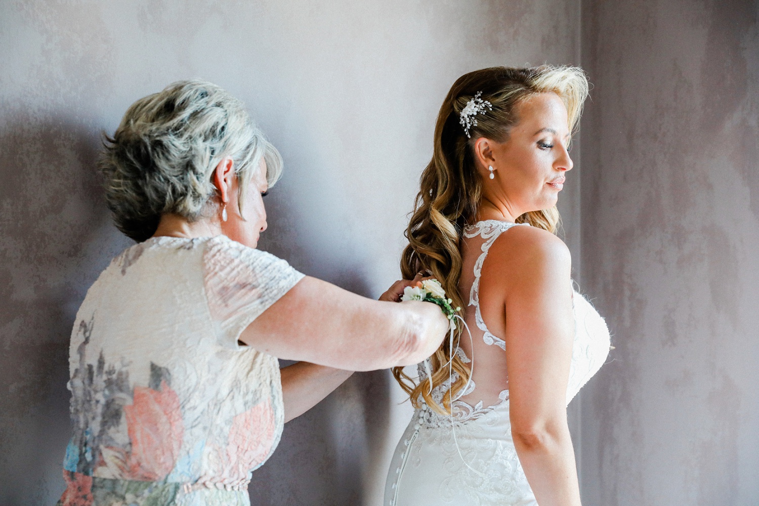 Bride helped into her Stella York wedding dress by her mother