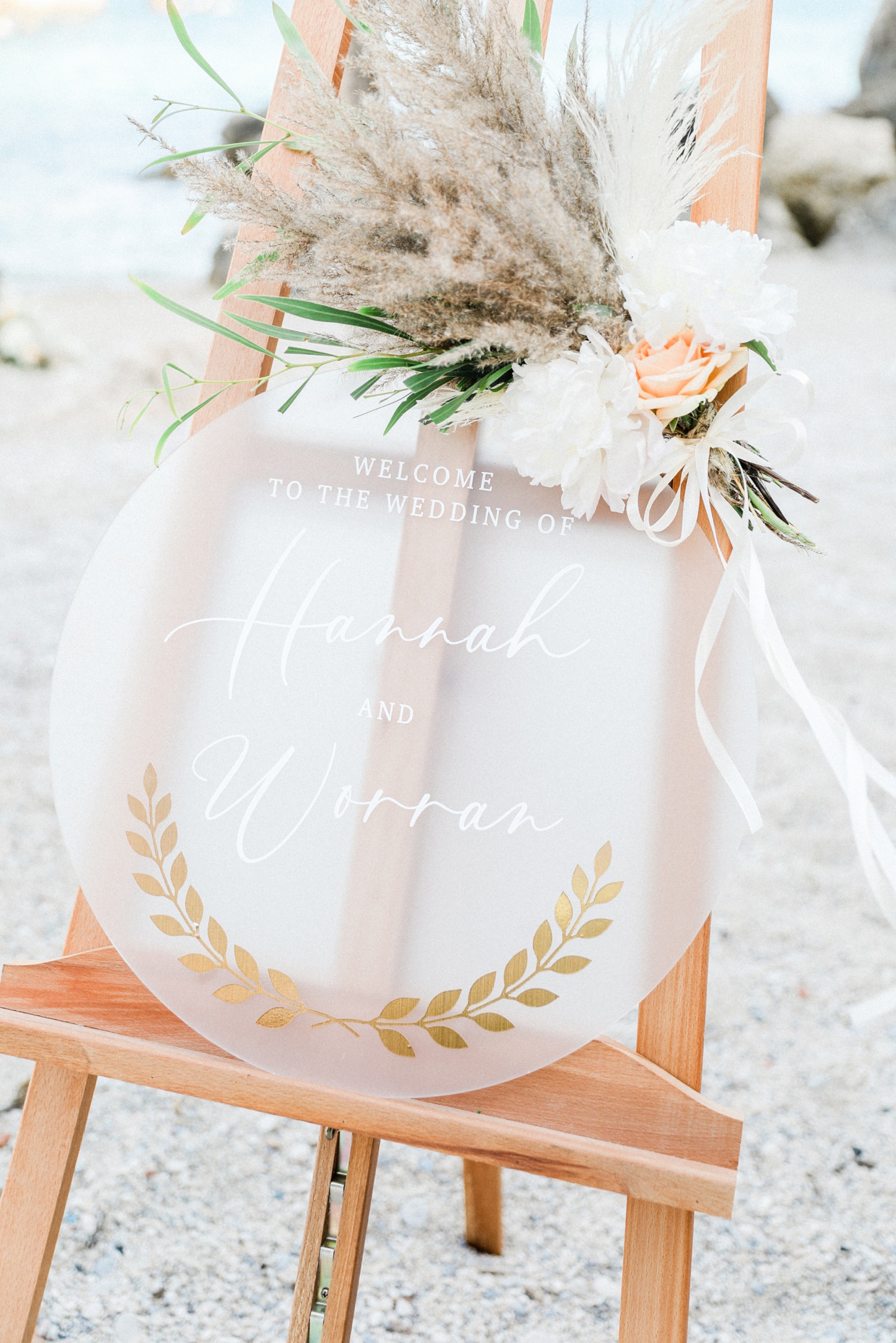 Perspex welcome sign with pampas decor at a beach wedding in Parga