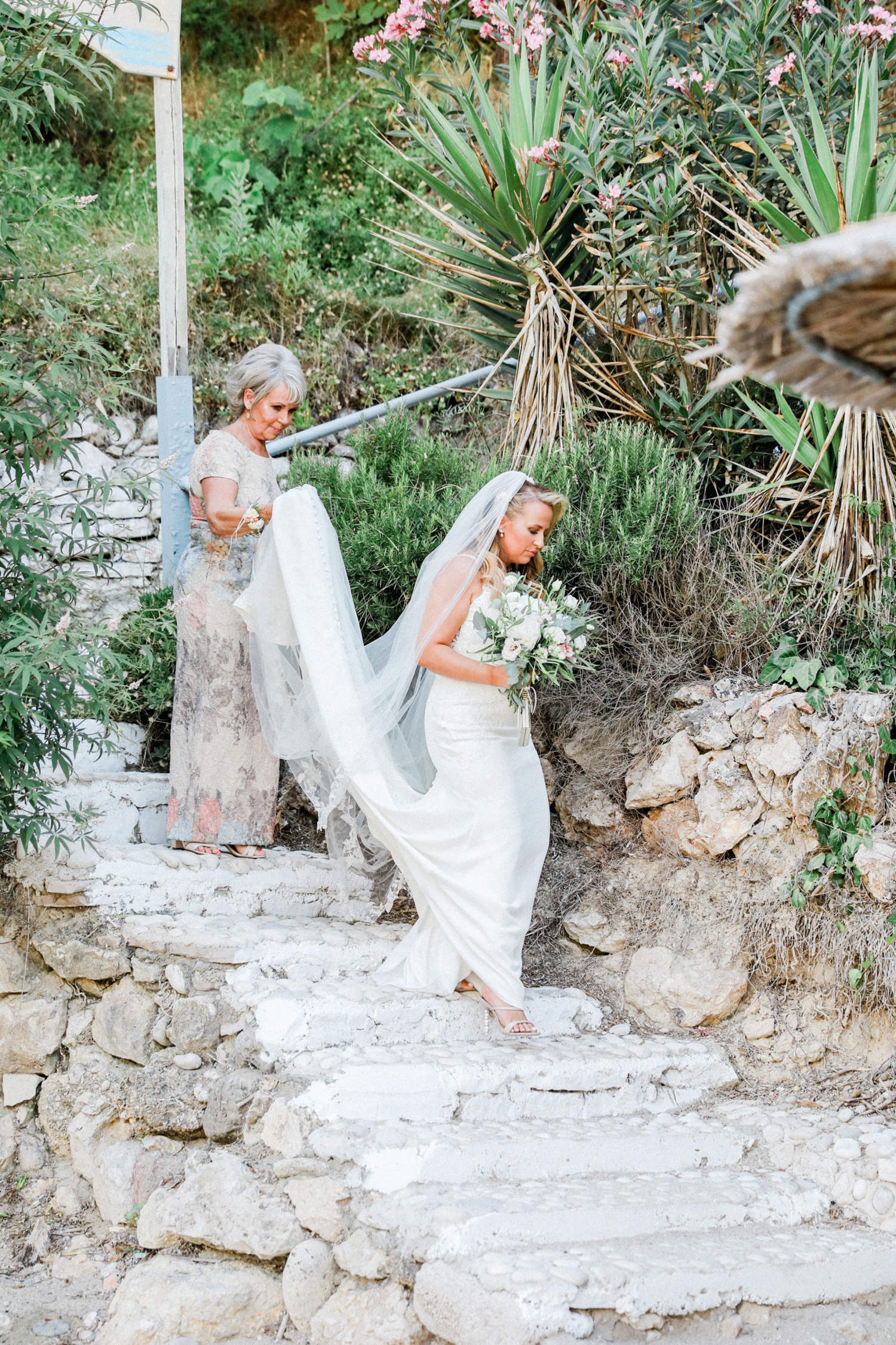 Bride and her mother arriving via cobbled stairs at a beach wedding in Parga