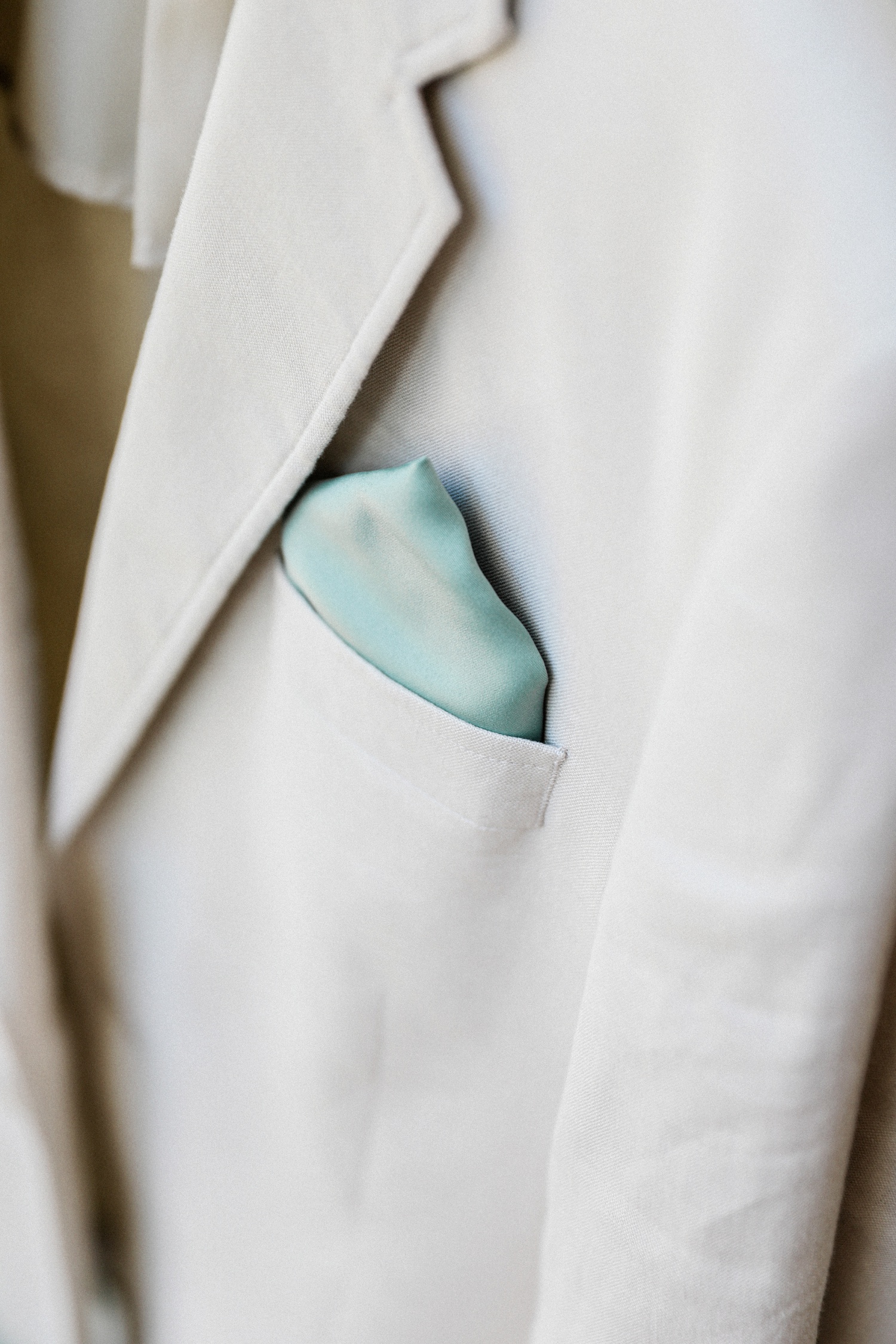 Grooms sage green pocket square in his stone coloured jacket