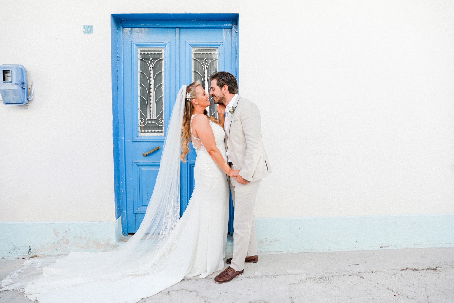 Bride and groom in front of a blue door on the streets of Parga
