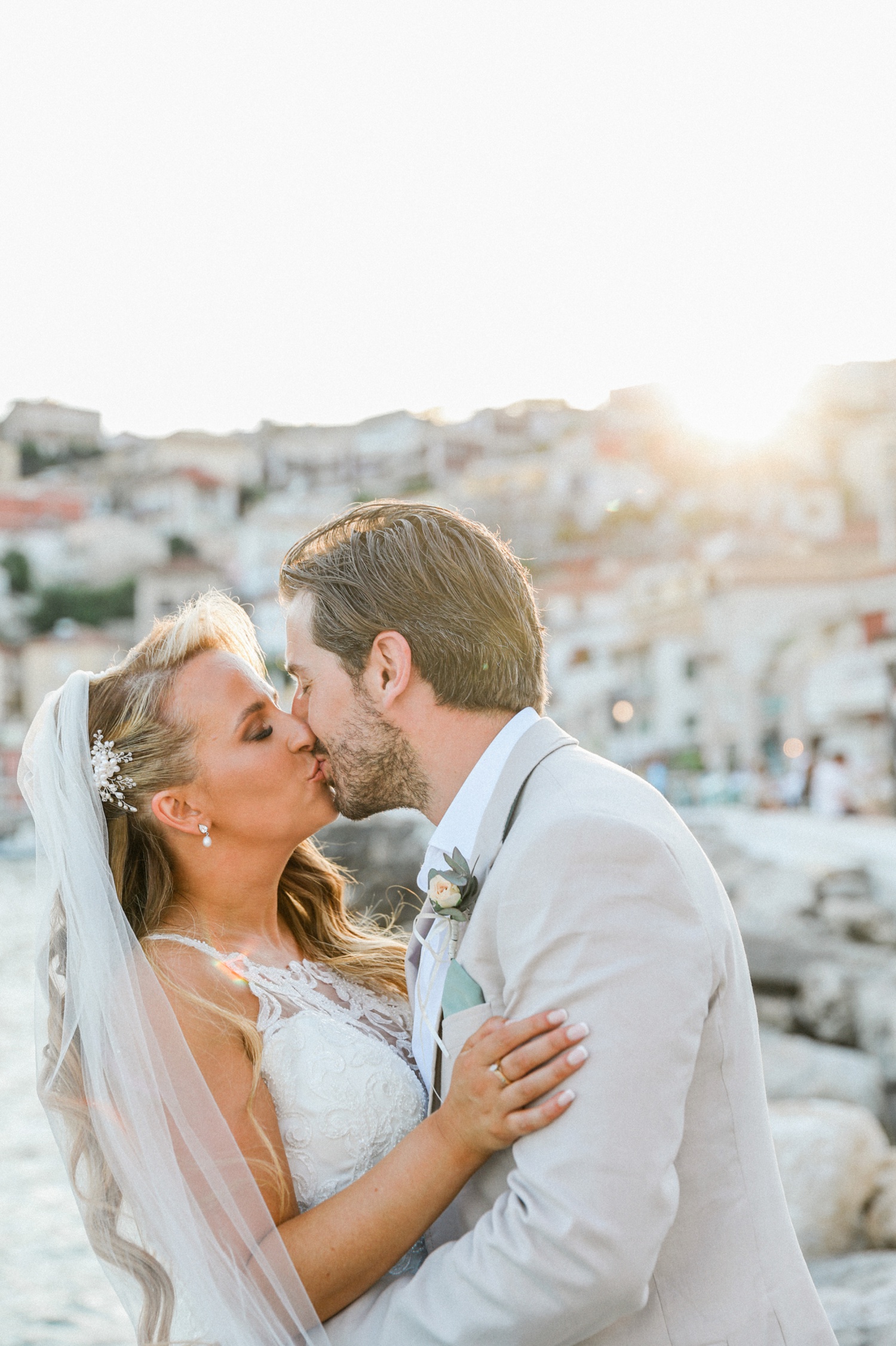 Bride and groom kissing at sunset in Parga harbour