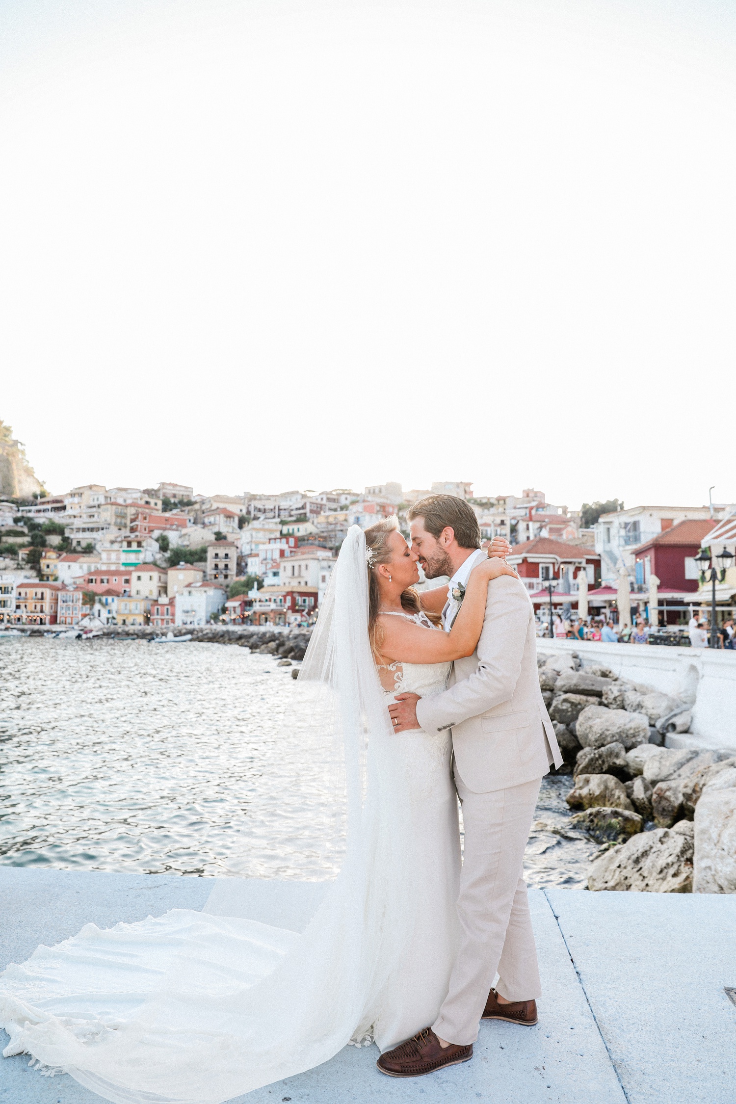 Bride wearing a Stella York gown with her groom in Parga harbour at sunset
