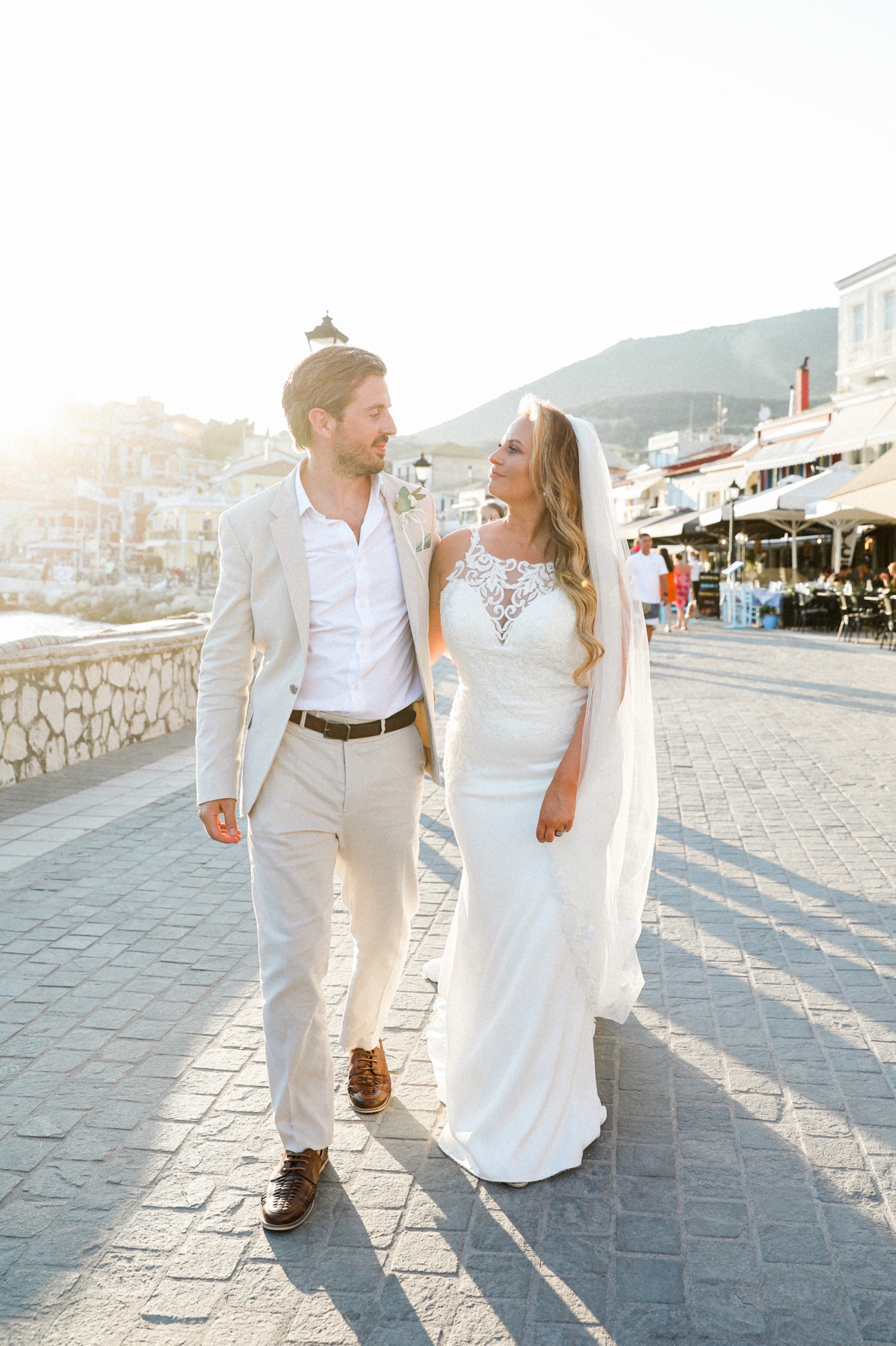 Bride and groom walk through the streets of Parga at sunset