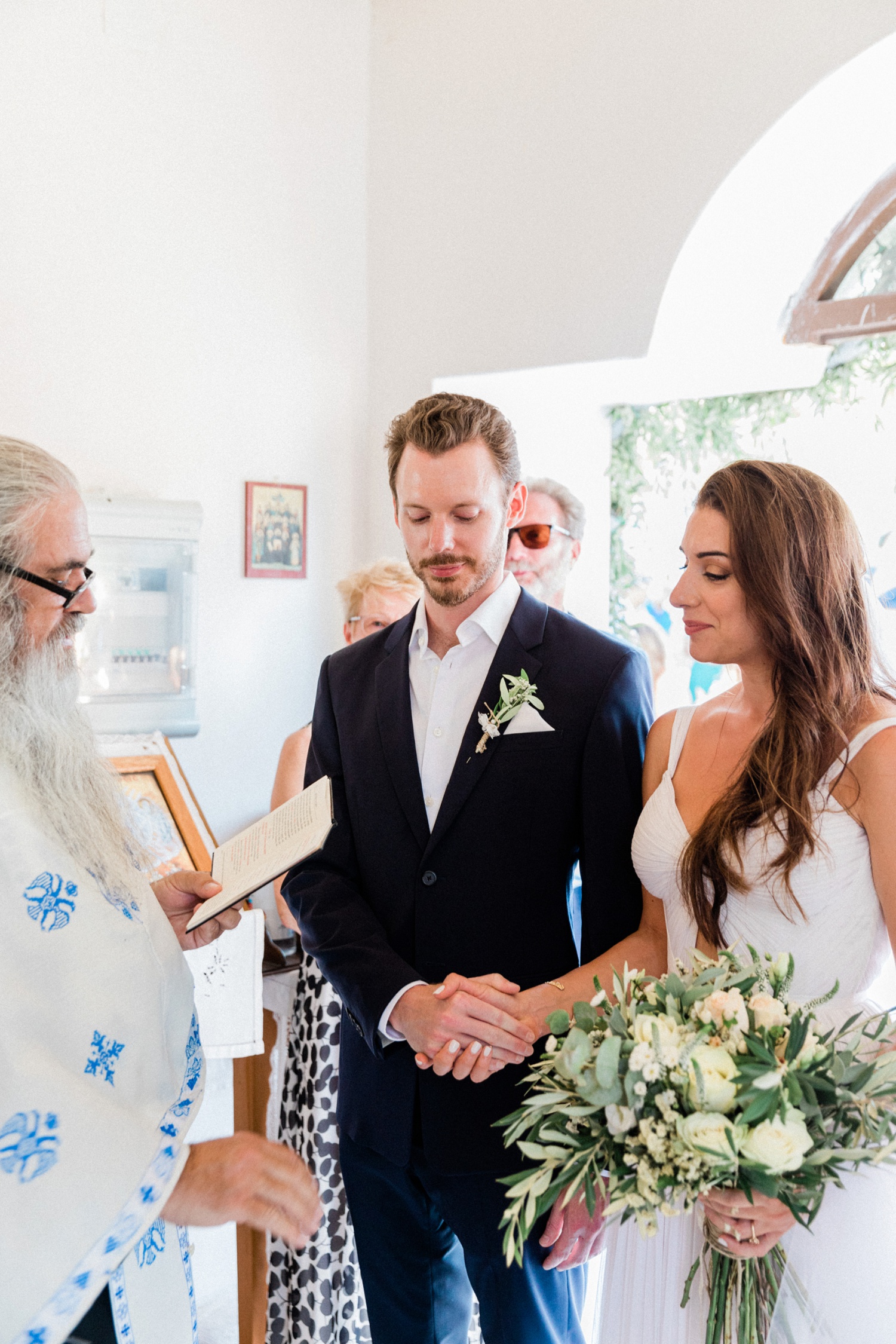 Bride and groom with the priest during their orthodox wedding ceremony on Ithaca
