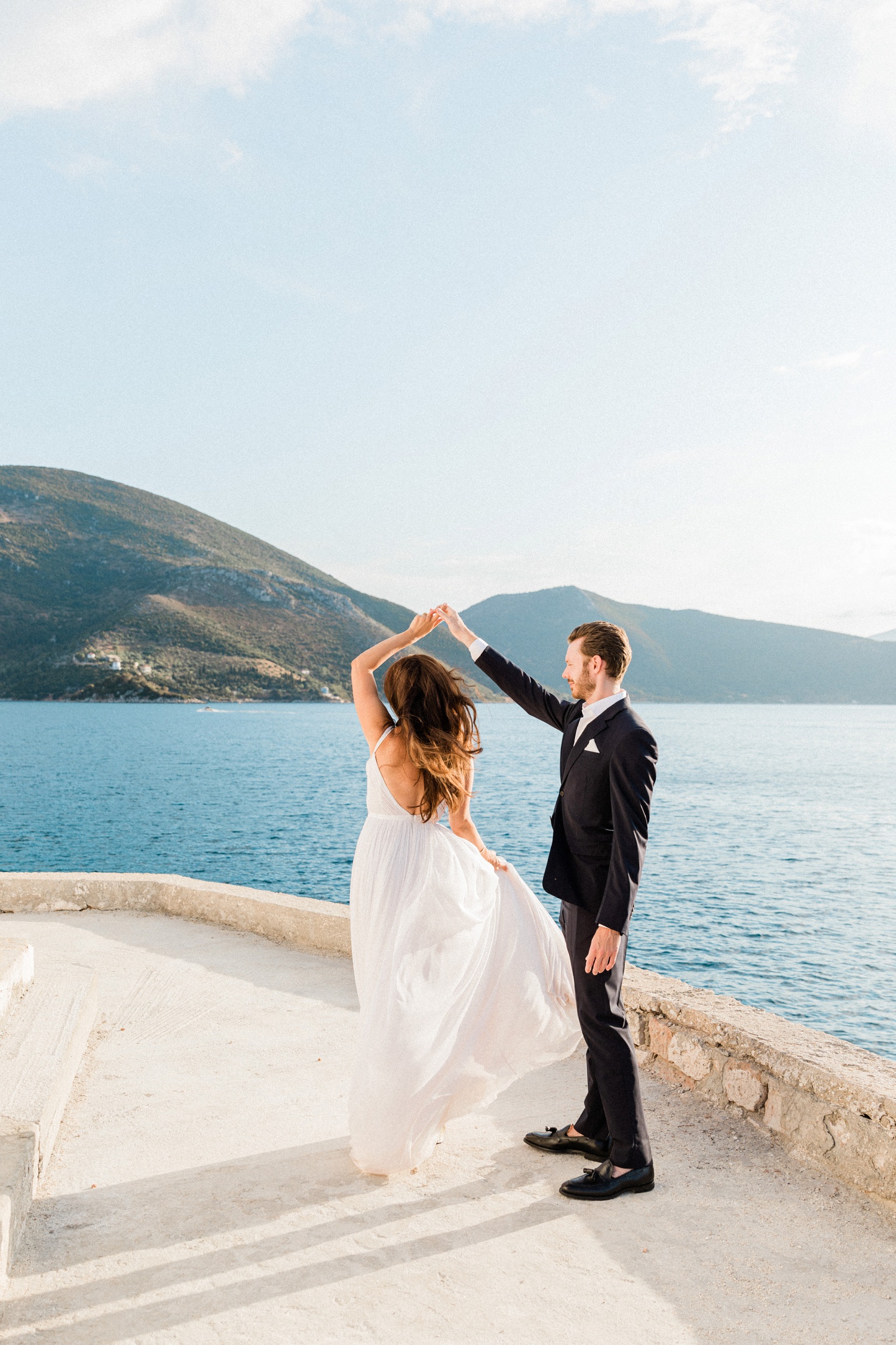 Bride and groom dance on a terrace above the sea with Ithaca in the distance