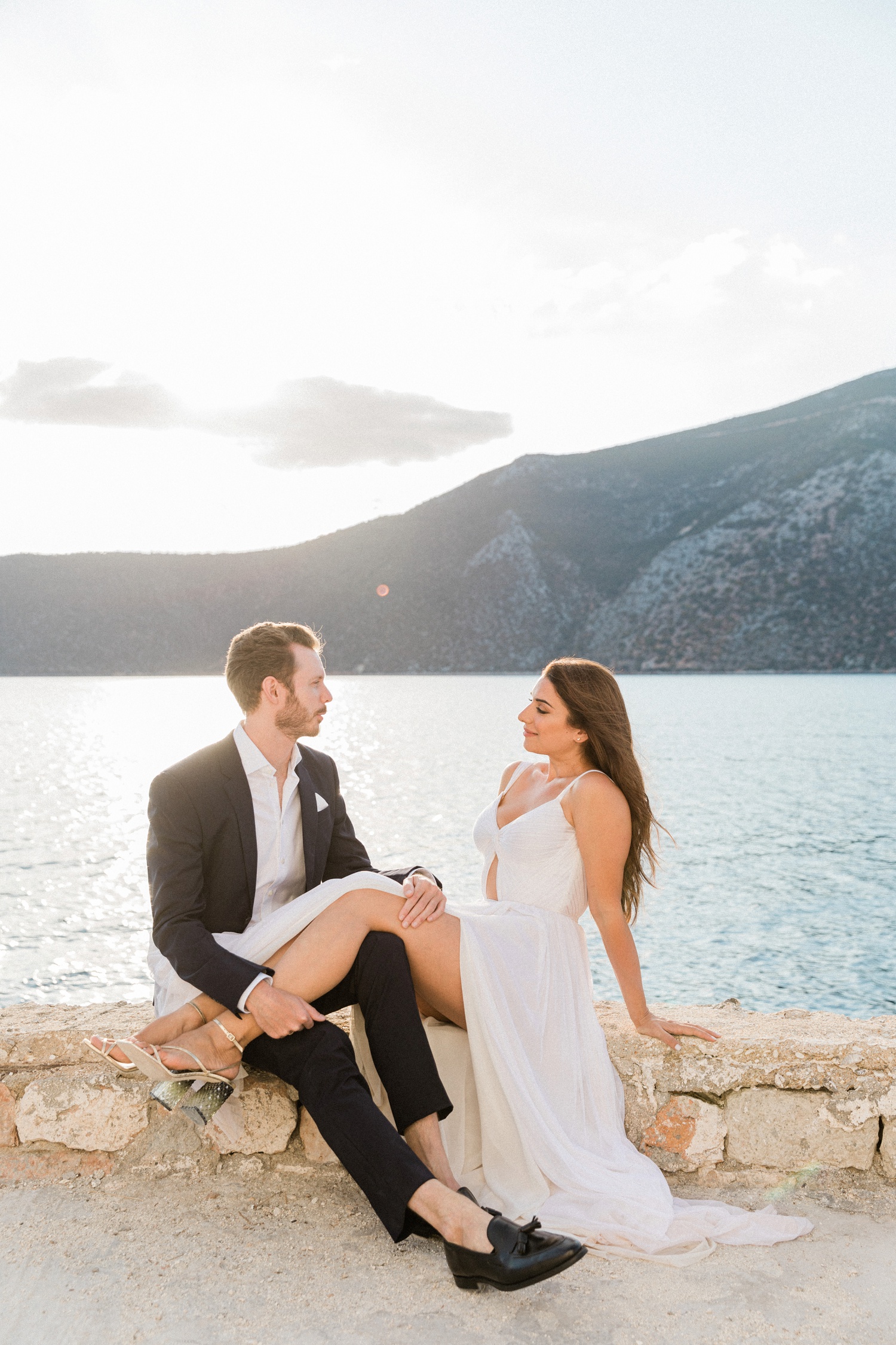 Couple sit on a terrace above the sea at sunset on Ithaca island in Greece