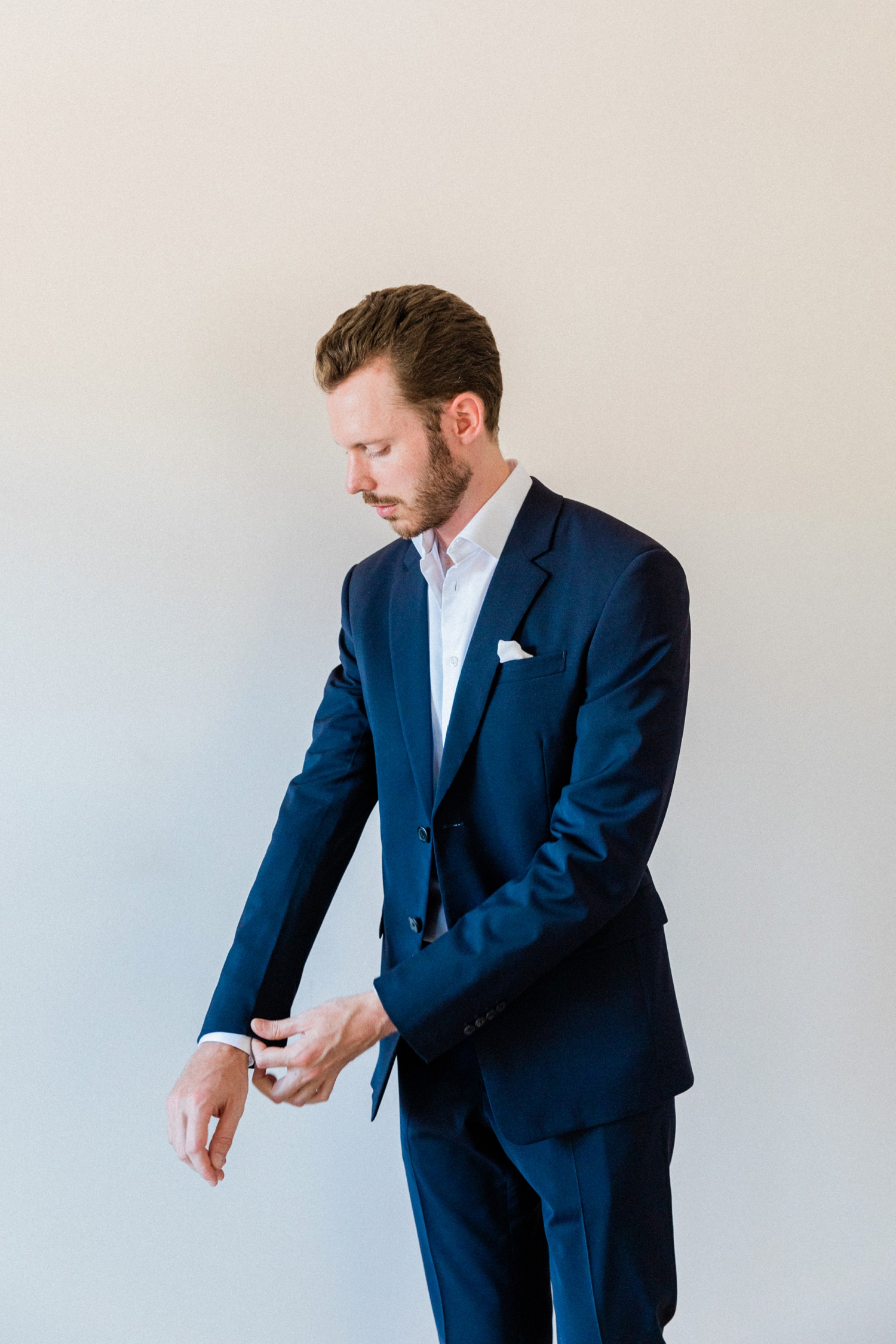 Groom puts on his navy Prada suit on the morning of his wedding on Ithaca