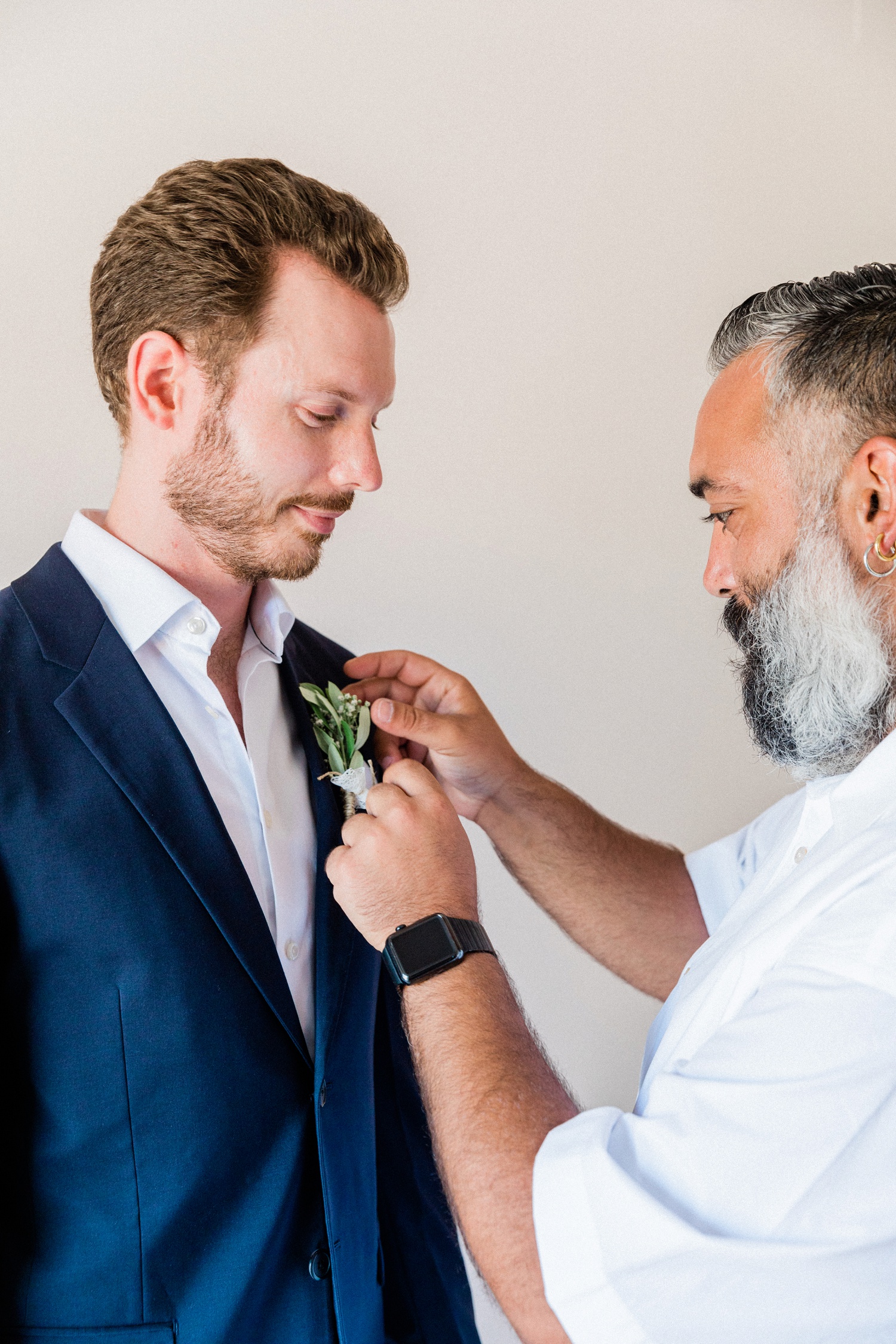 Best man pinning an olive buttonhole to the grooms jacket