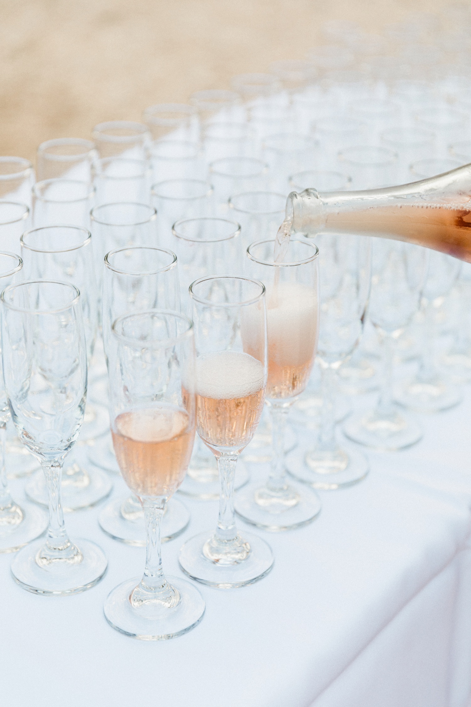 Rose champagne being poured during cocktail hour at an olive grove wedding on Ithaca