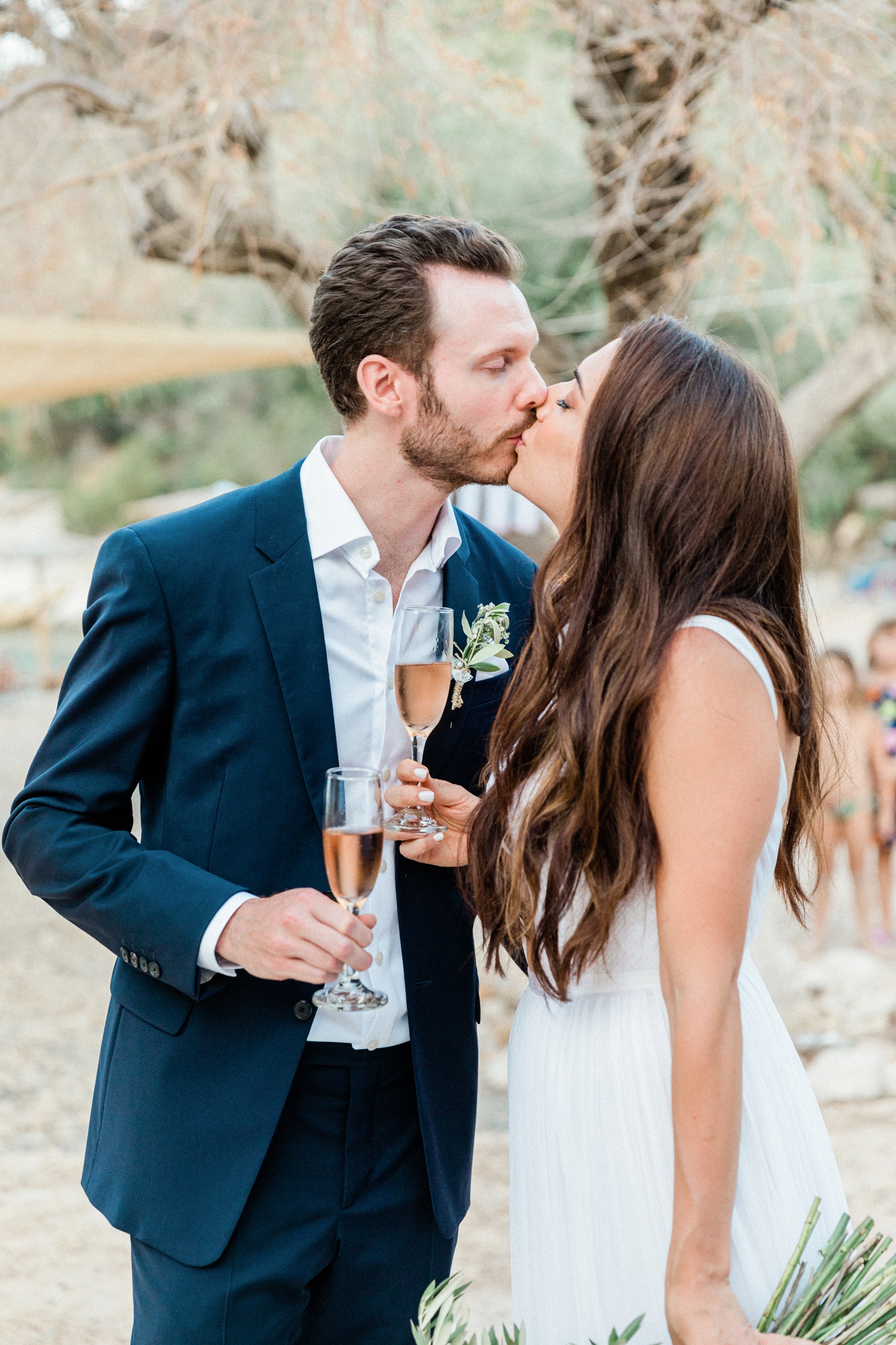 Couple kiss during their wedding cocktail hour at Kirki on Filiatro beach in Ithaca