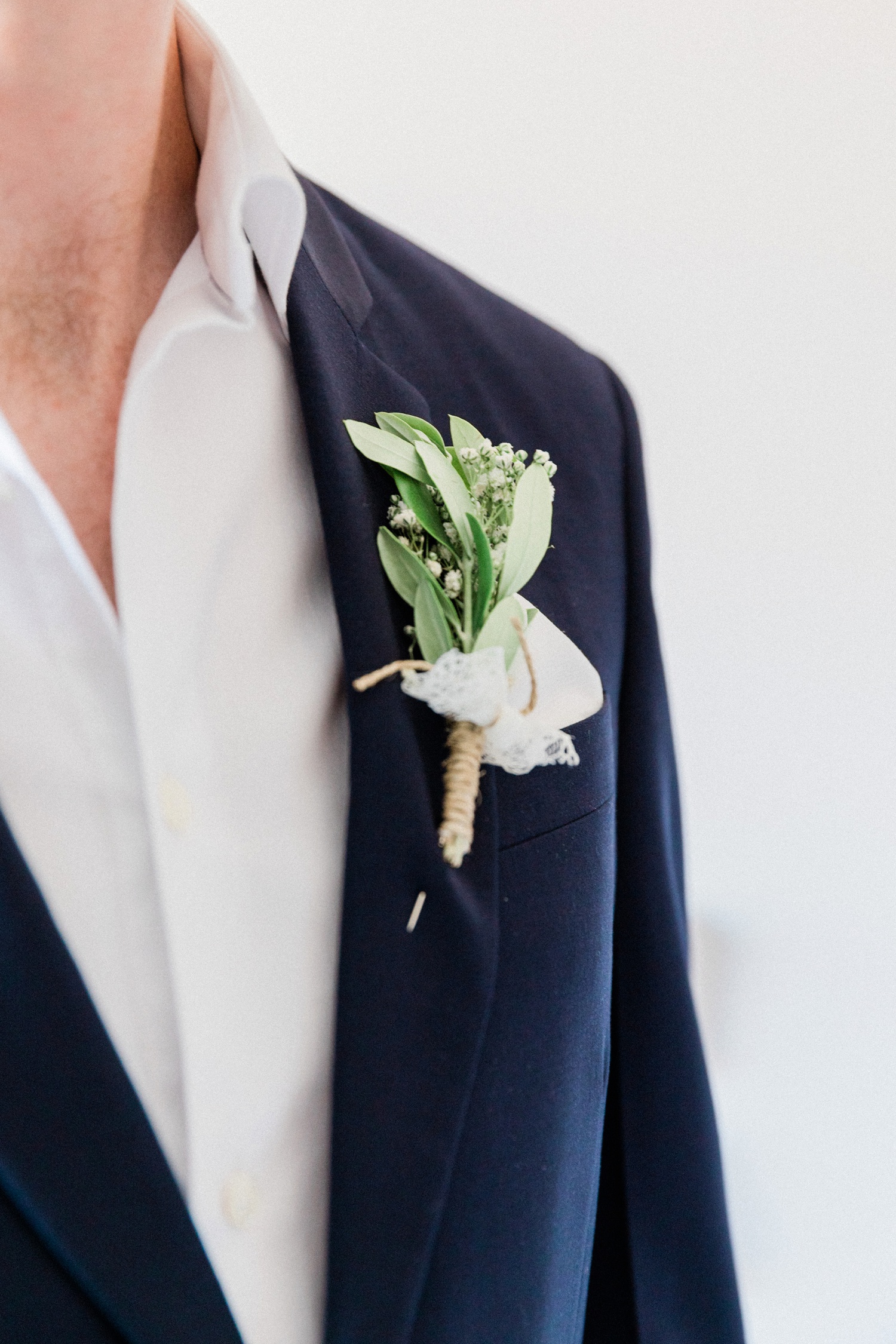 Grooms olive buttonhole on his navy Prada suite