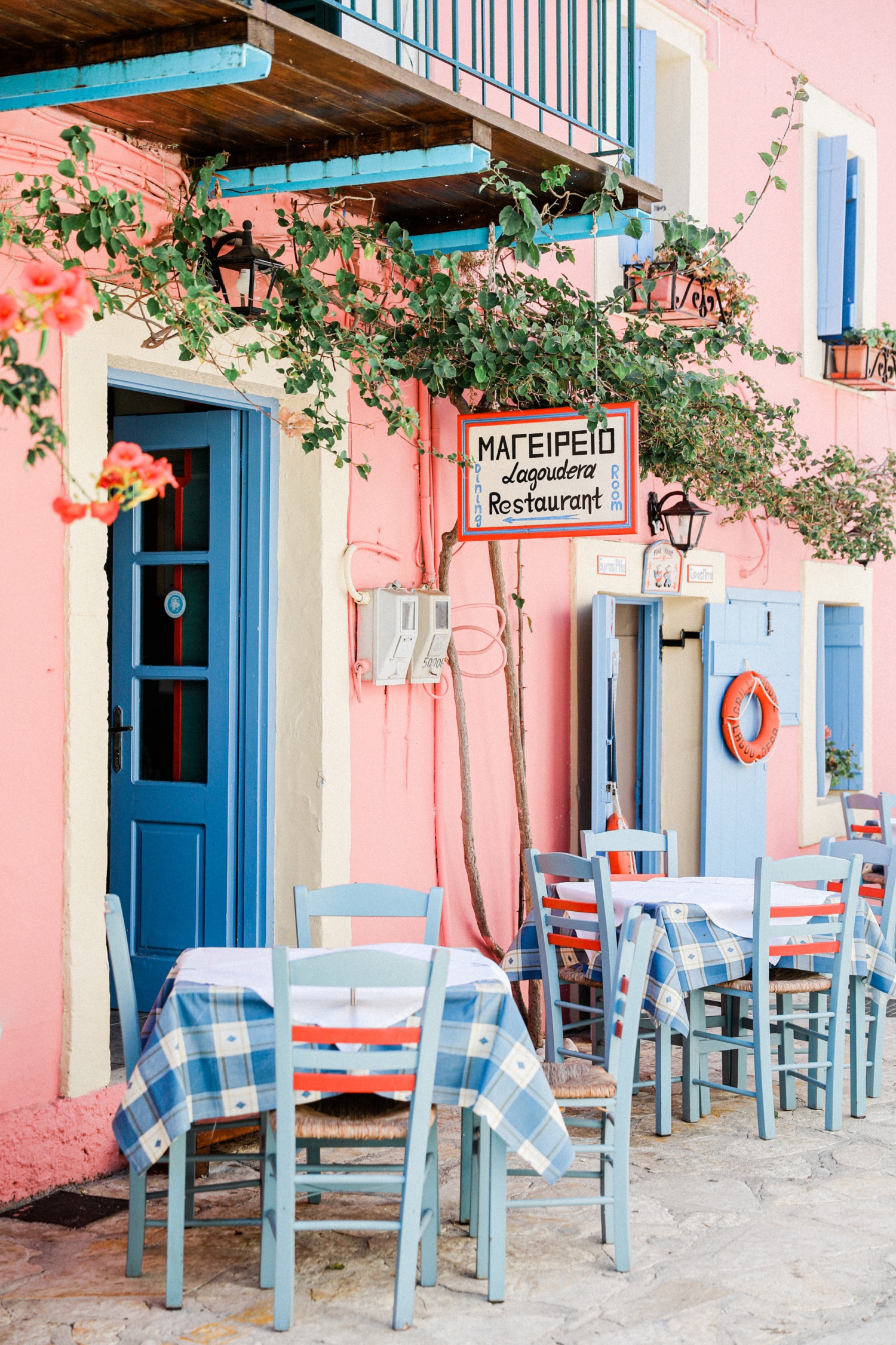 Blue and peach Fiskardo gyros shop with pale blue tables and chairs outside