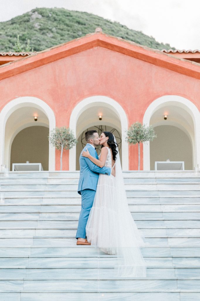Bride and groom kiss on the staircase to the poolhouse during their Villa Veneziano Wedding