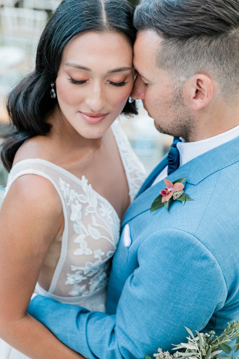 Portrait of a bride and groom hugging with their eyes closed in grounds of Villa Veneziano